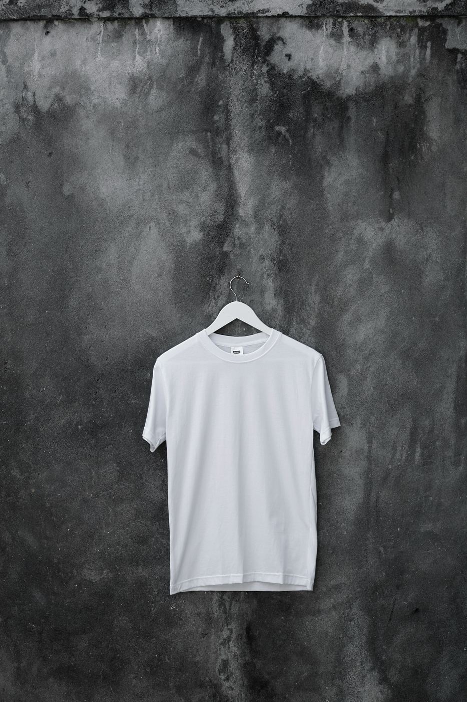 White essential t-shirt hanging on a studio wall